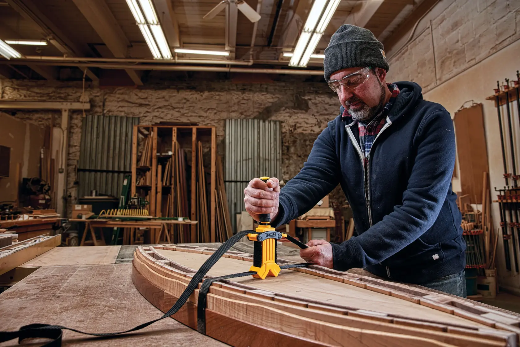 Profile of  15 foot Band Clamp being used on wooden structures by a person in a workshop.