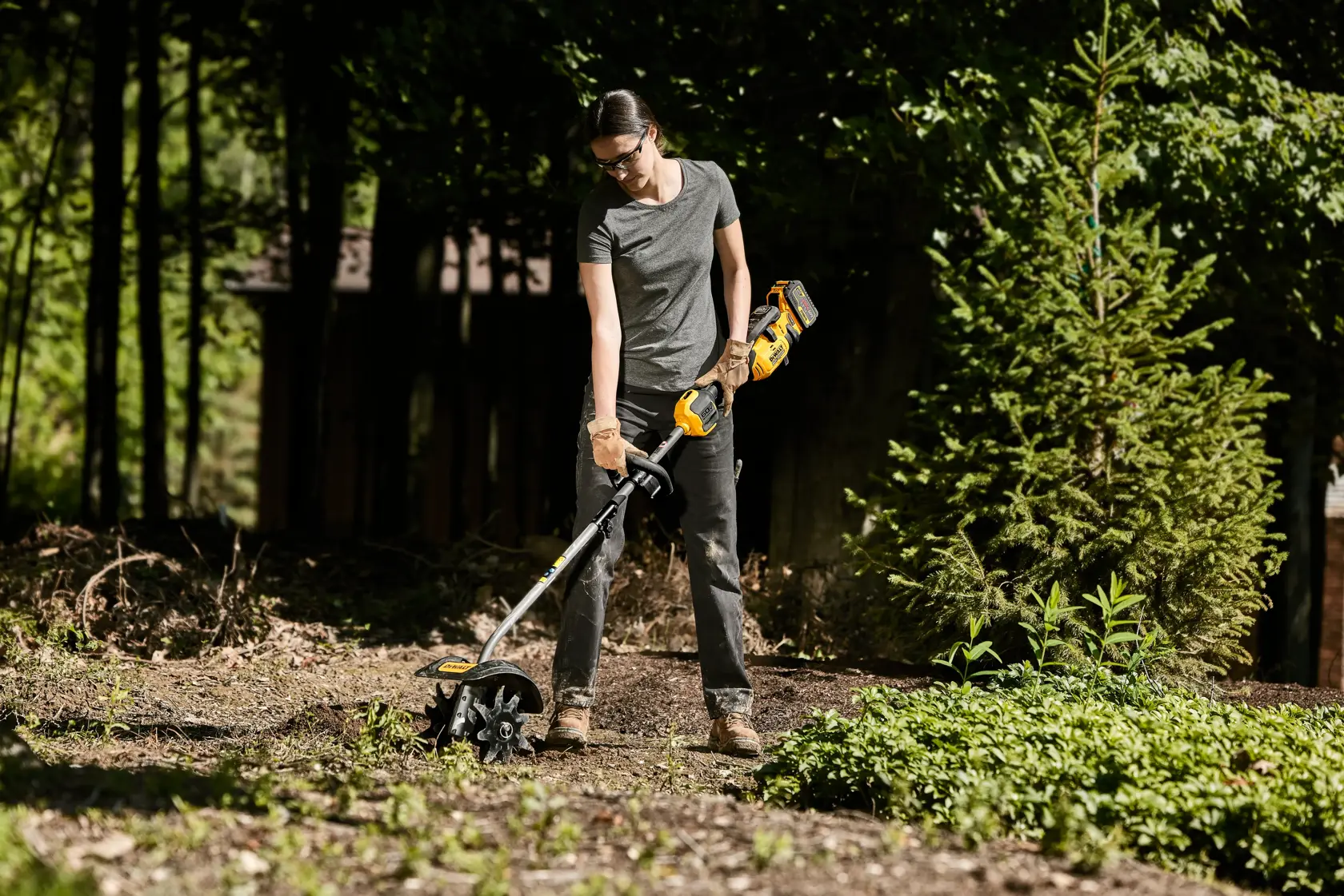 DEWALT cultivator attachment head being held by a woman in her yard getting ready to work the soil. 