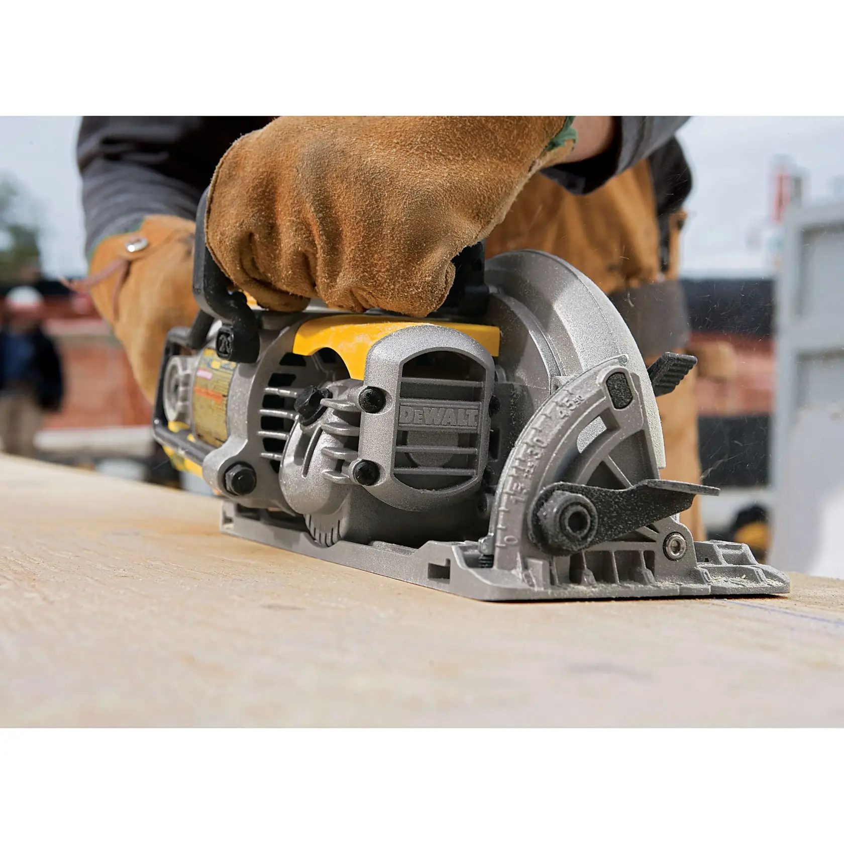 Close-up of a person wearing brown work gloves using a DEWALT circular saw to cut a piece of wood, with construction materials visible in the background.