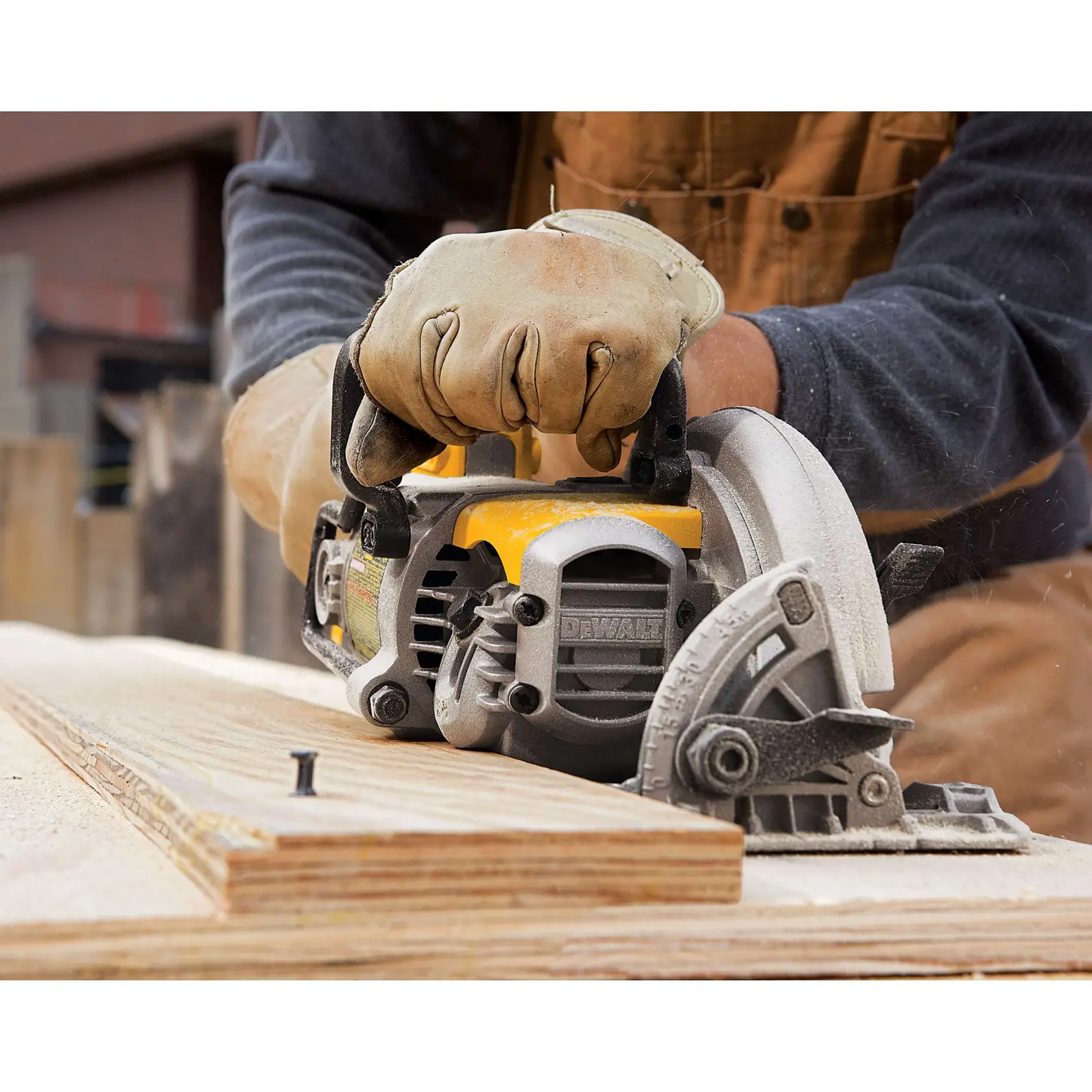A person wearing work gloves uses a DEWALT circular saw to cut a piece of plywood. Sawdust is visible around the cutting area, and the scene appears to be a woodworking setting.