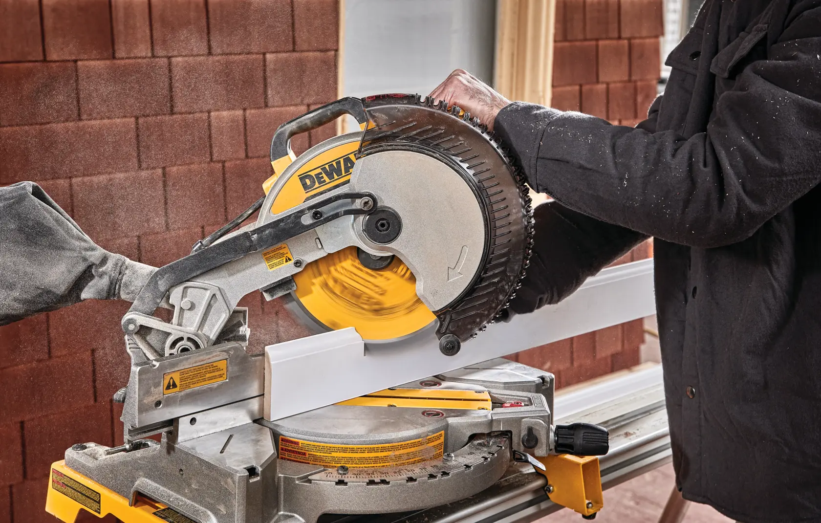 Electric single bevel compound miter saw being used to cut wood.