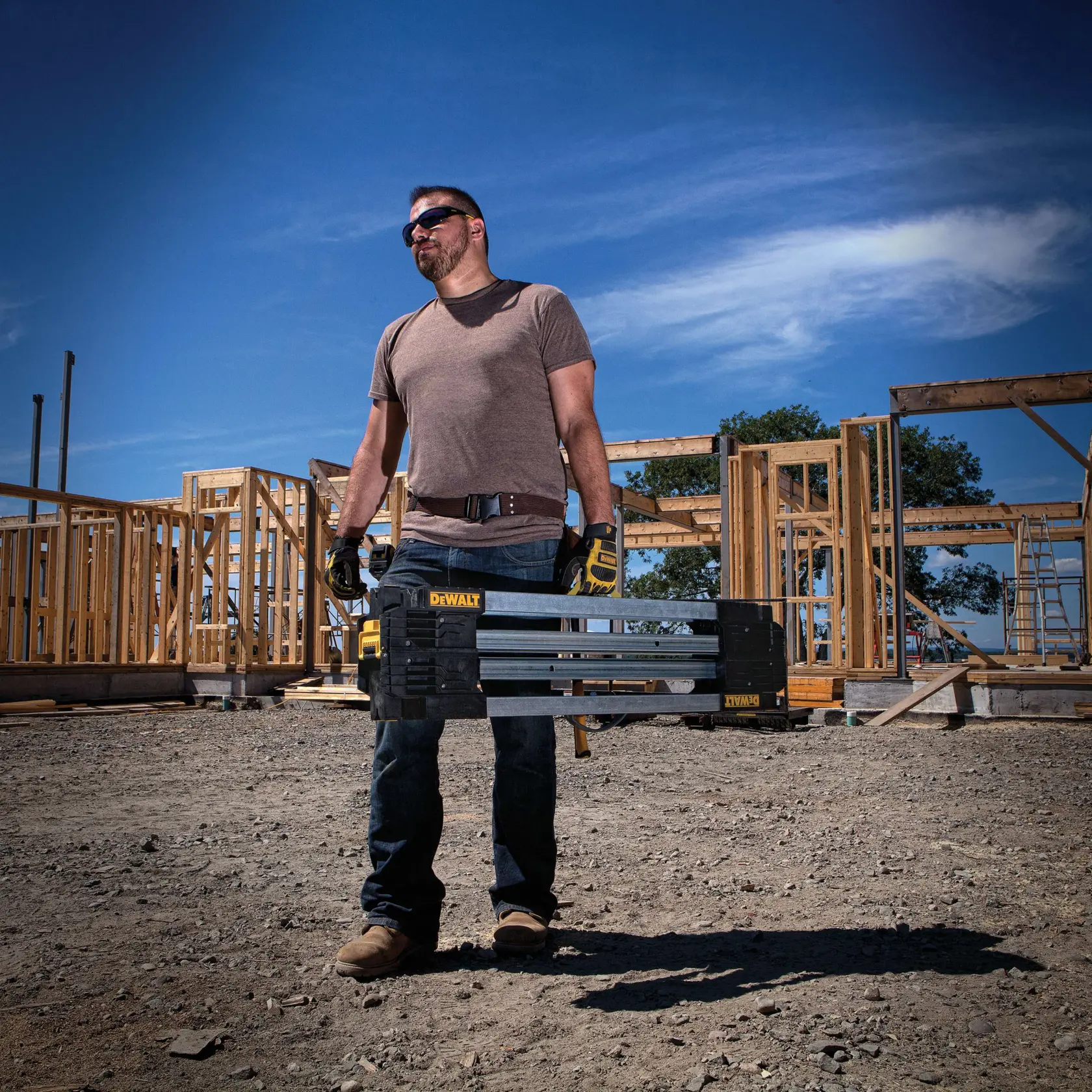 Folded metal folding sawhorse being carried by a person at a worksite.