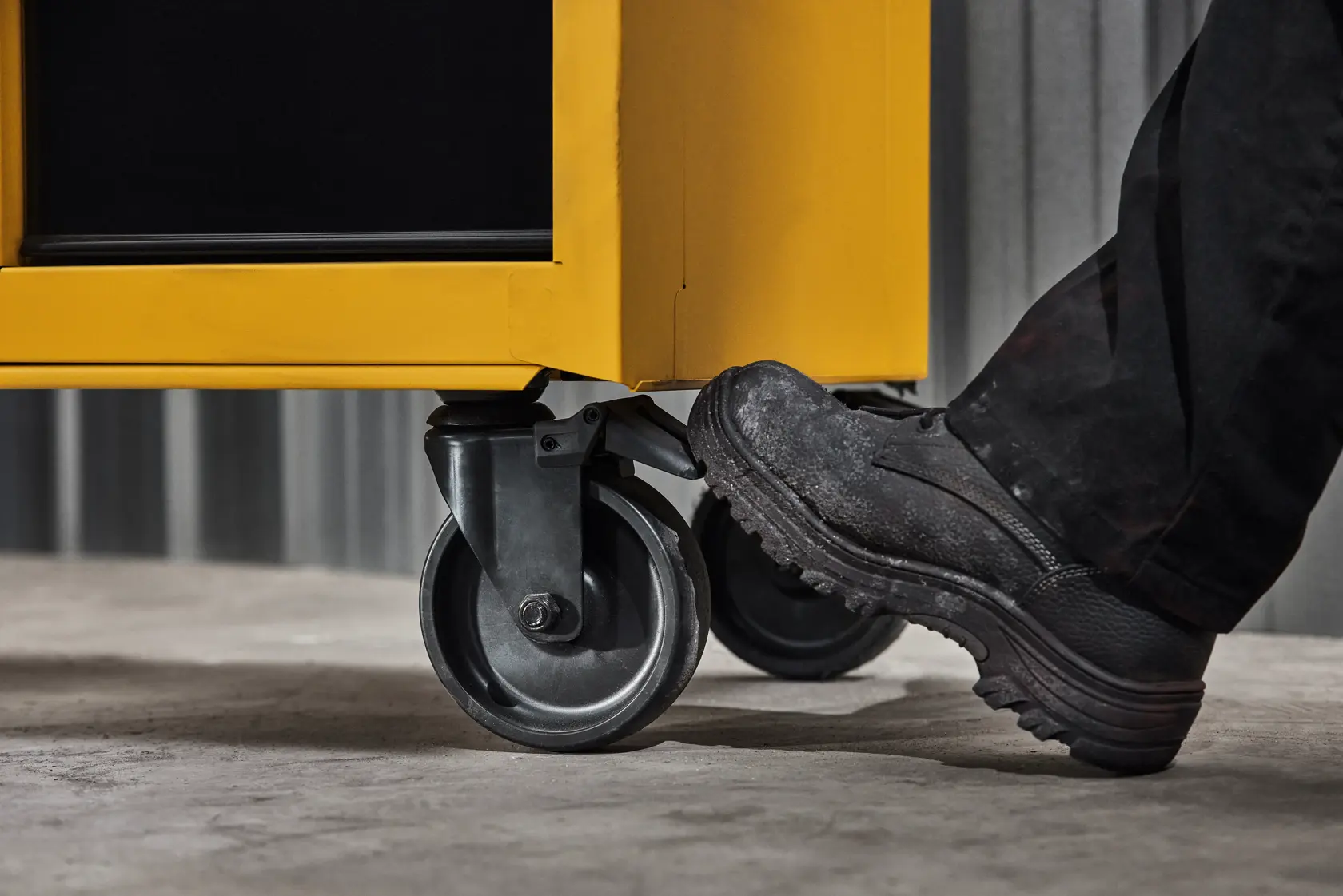 A Person's Foot Stepping On a Pedal On a DEWALT Cabinet Wheel