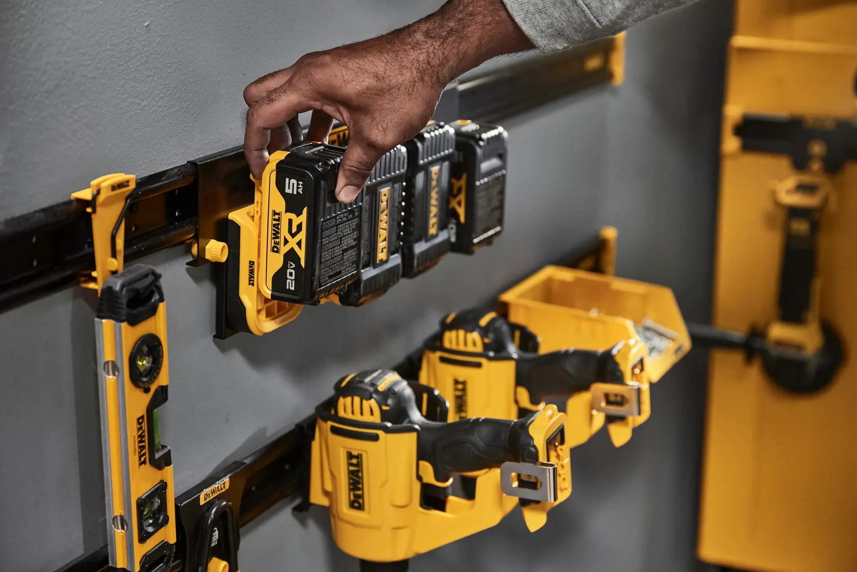 A Person Grabbing a DEWALT Battery Off of the DEWALT Metal Rail