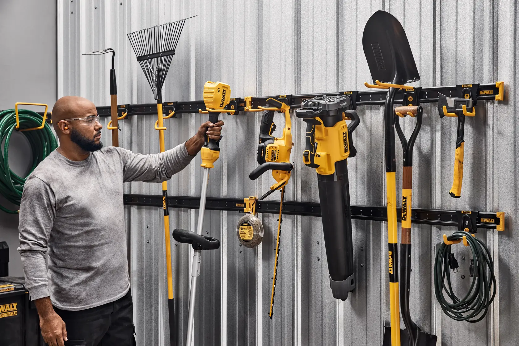 A Person Grabbing an Outdoor Tool off of a DEWALT Metal Rail Featuring Lawn/Garden Kits
