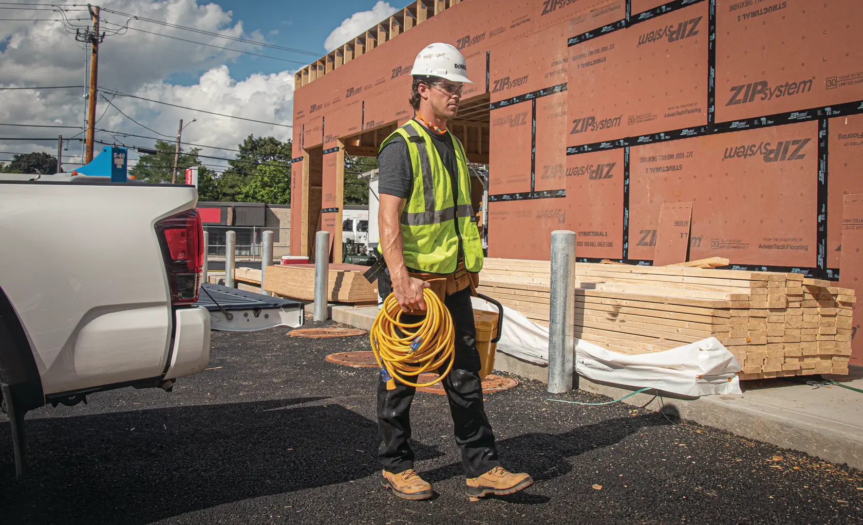 50 feet twelve thirds Lighted C G M Extension Cord being carried by worker at worksite.