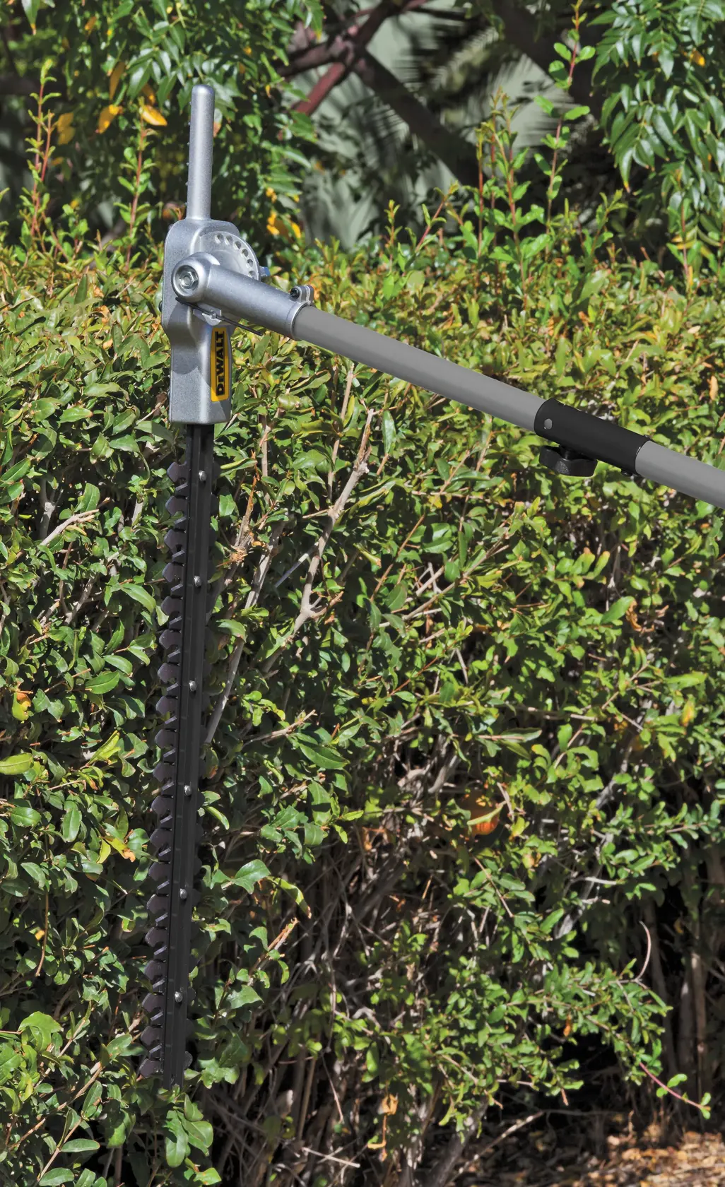 27 cubic centimeters 2 Cycle 22 inch Gas Hedge Trimmer with Attachment Capability being used to trim a hedge.