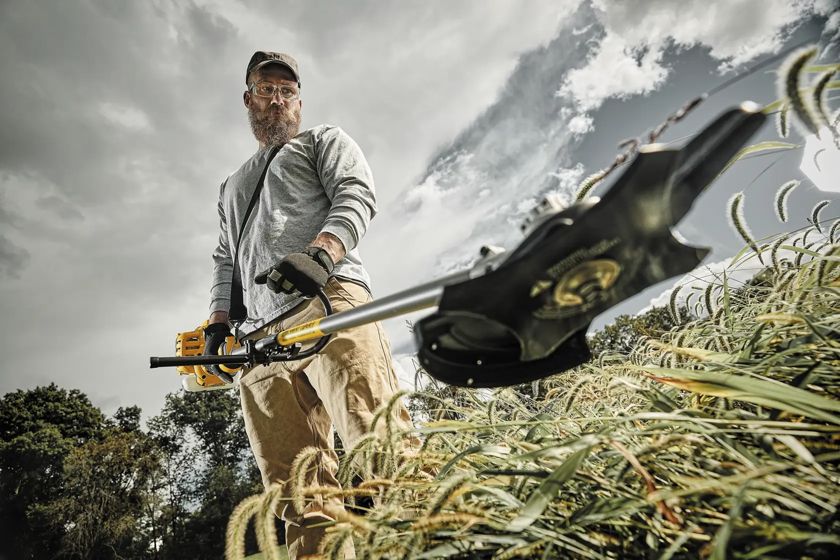 Gas Brushcutter with Attachment Capability being used by person to cut through dense overgrowth outdoors.