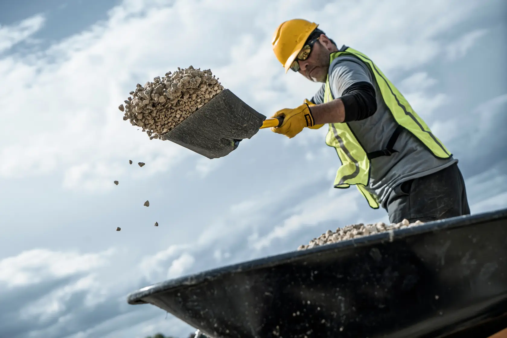 49 inch Fiberglass Handle Transfer Shovel shoveling rocks in side view in safety vest and hard hat