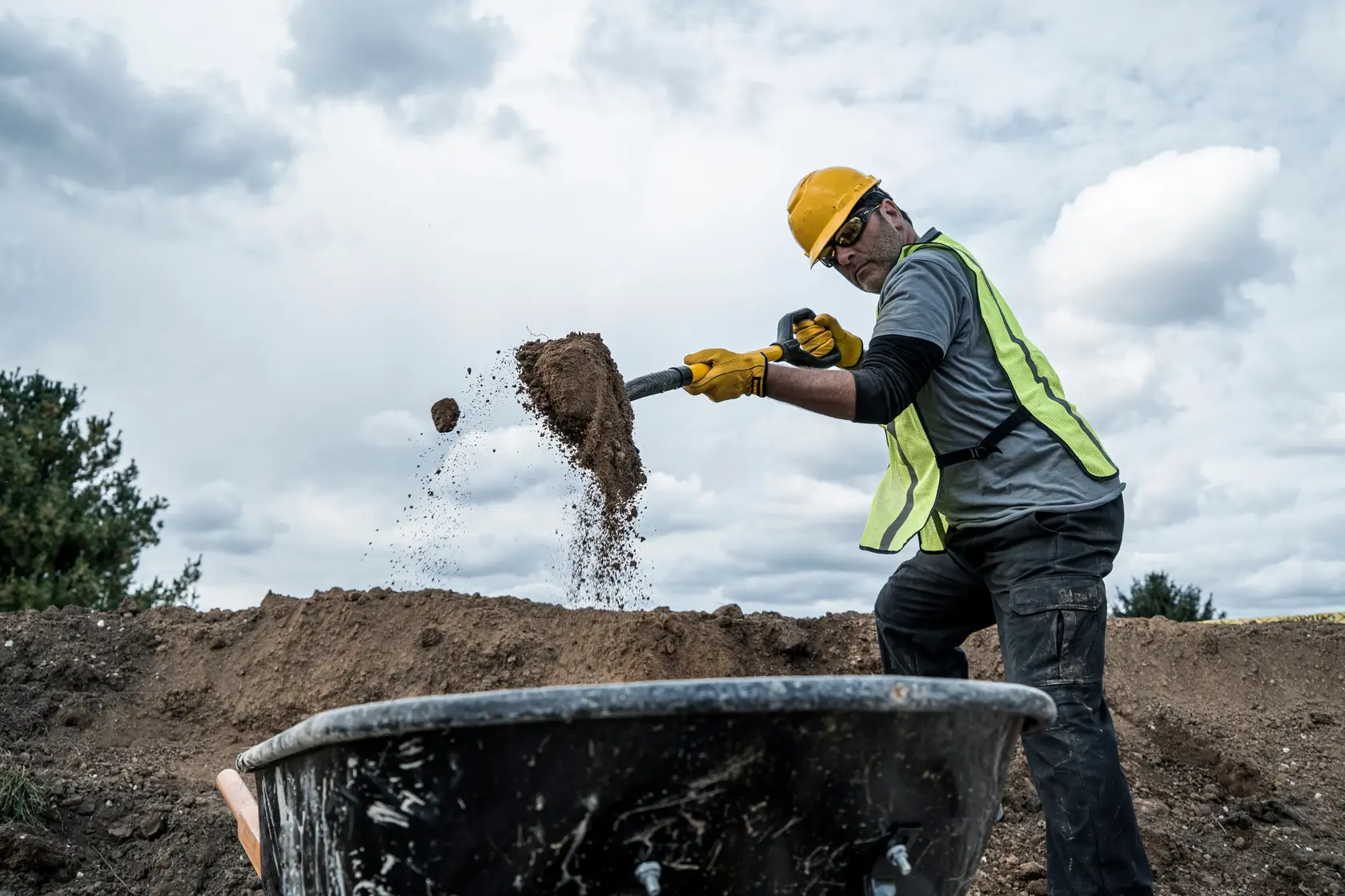 32 inch Fiberglass D-Handle Transfer Shovel shoveling dirt into wheelbarrow with gray shirt in front view