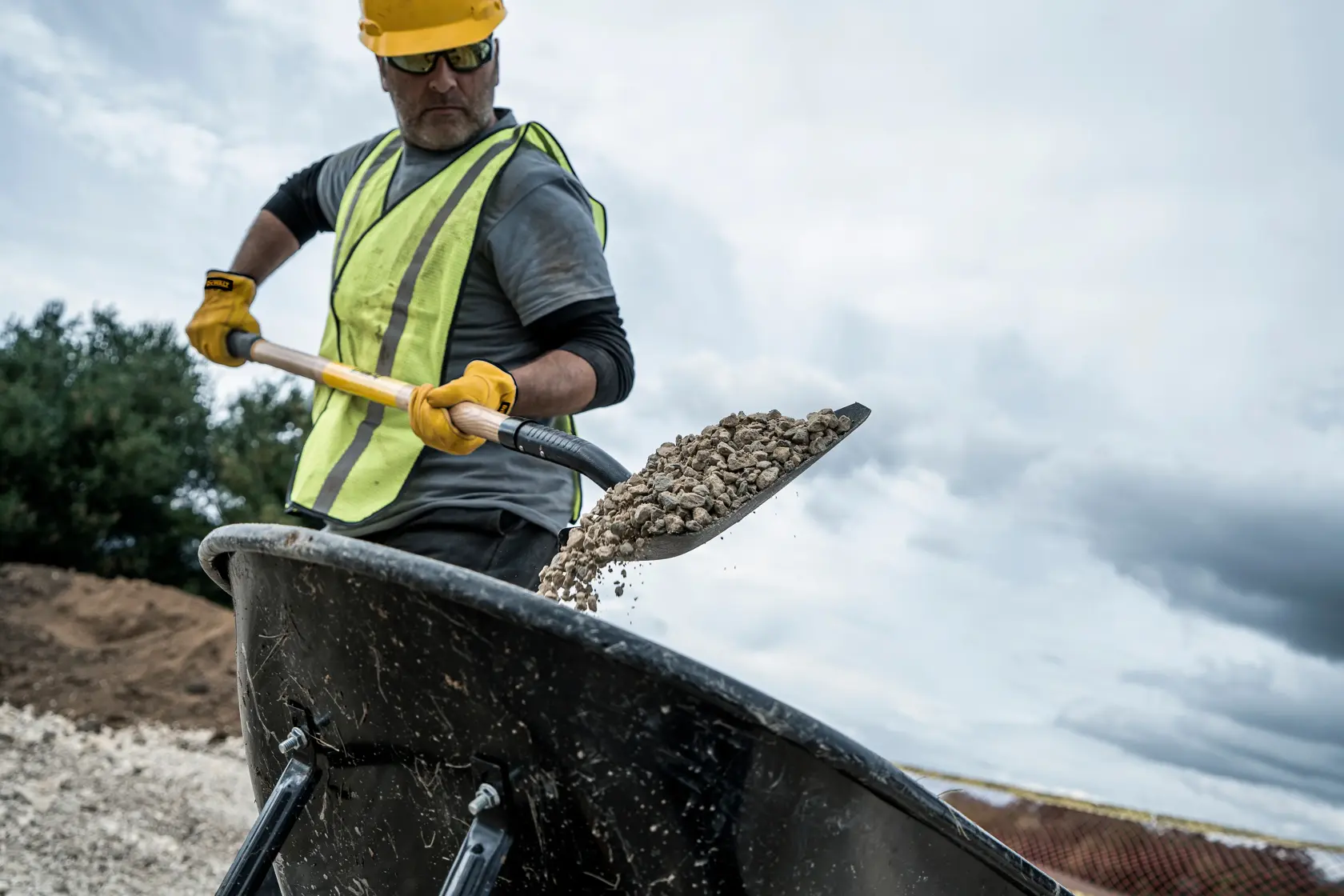 49 inch Wood Handle Transfer Shovel shoveling dirt into wheelbarrow with gray shirt in front view