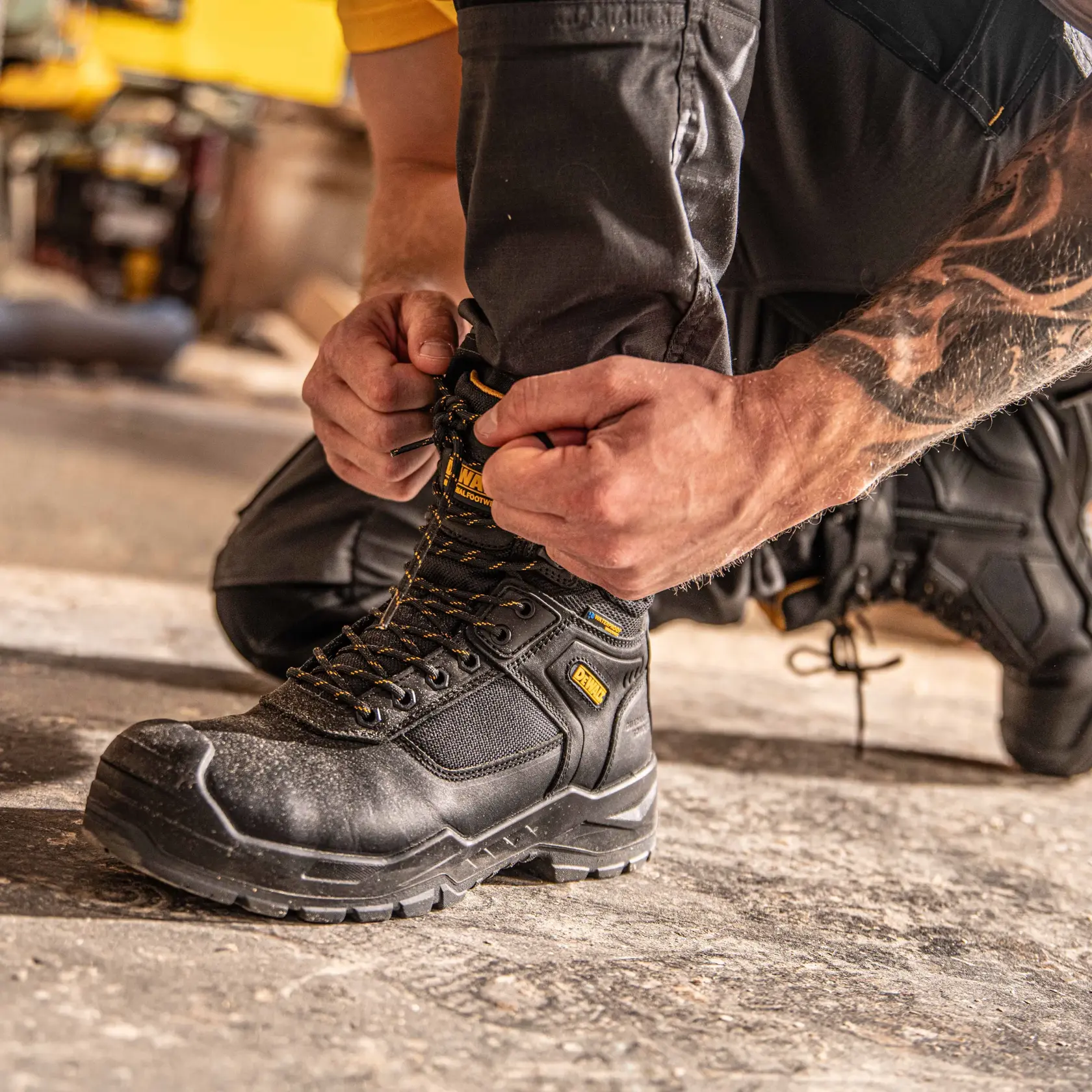 Side view facing left of the DEWALT Bryant men’s side zip safety boot in black on model on location