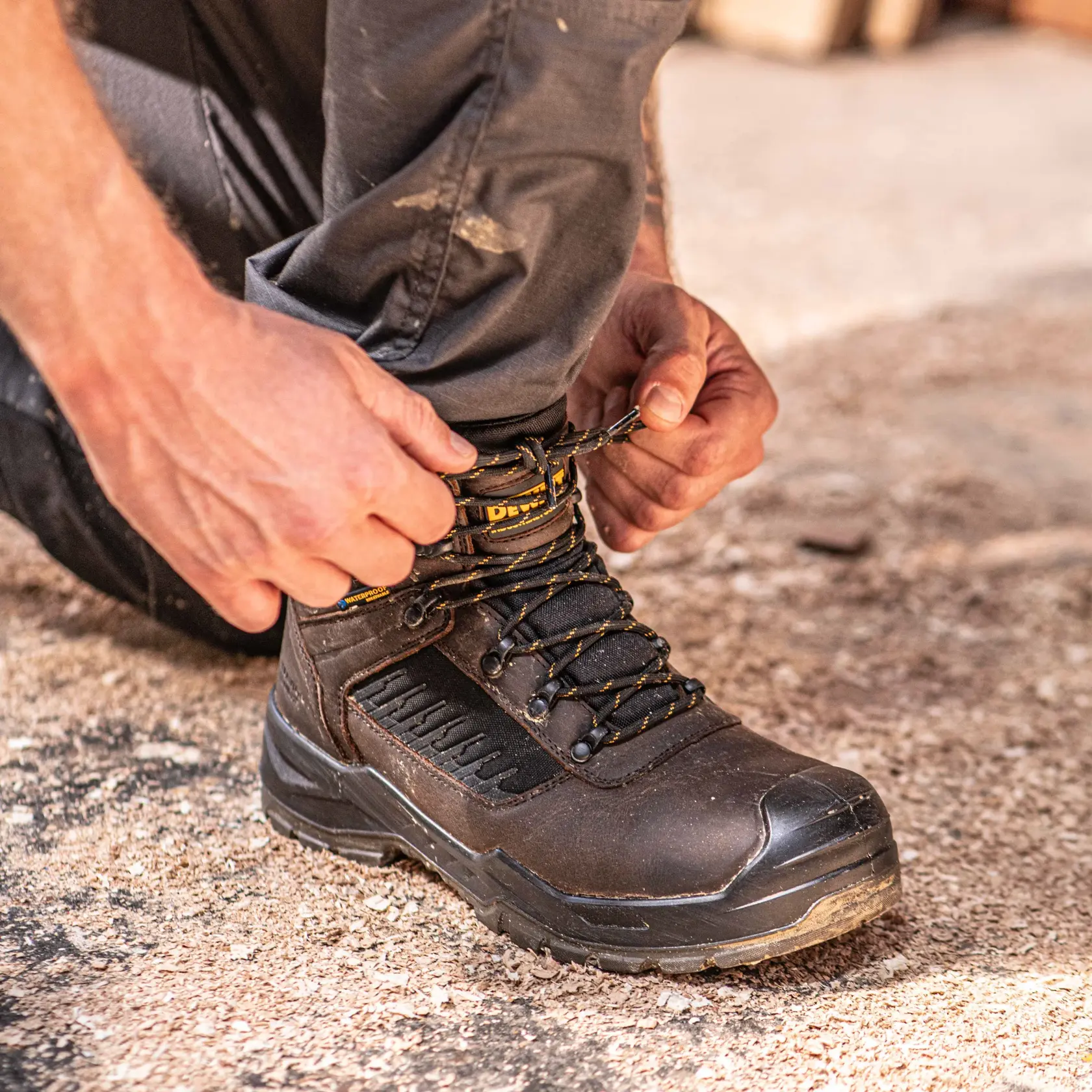 Front view facing right of the DEWALT Reynolds men’s safety boot in brown on model on location