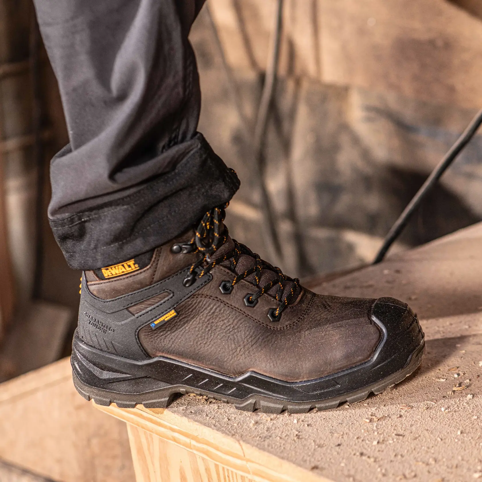 Side view facing right of the DEWALT Hayes men’s safety boot in brown on model on location