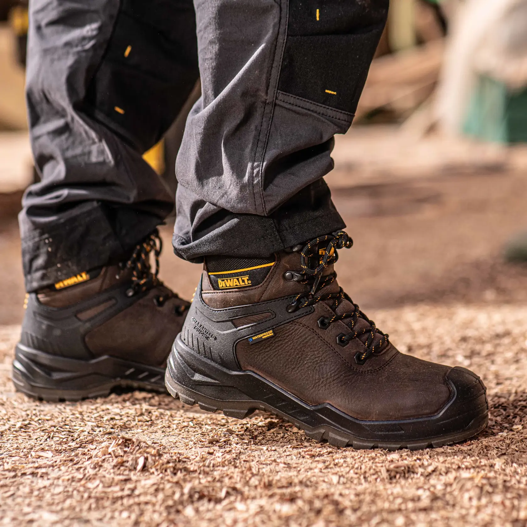 Side view facing right of the DEWALT Hayes men’s safety boot in brown on model on location