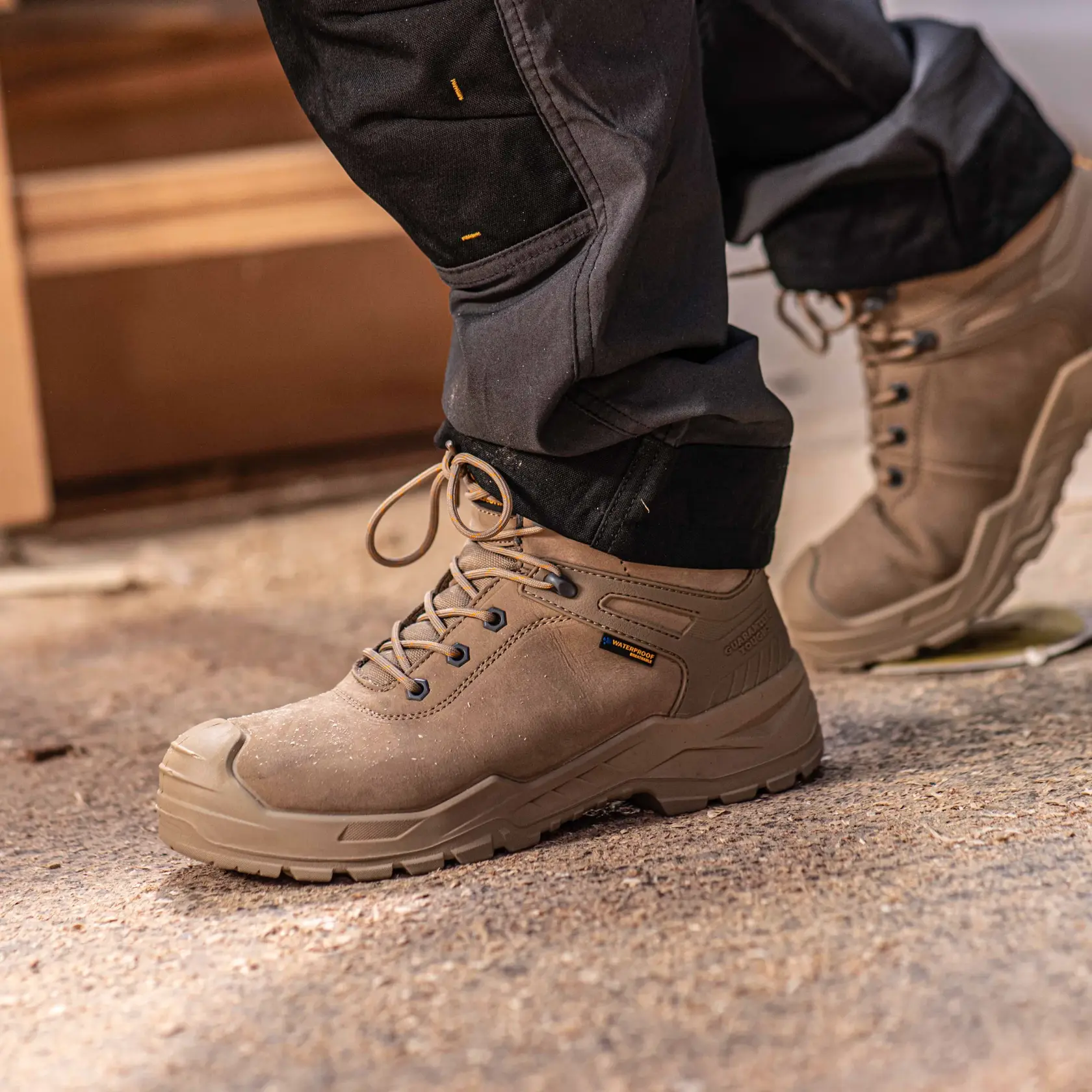 Side view facing left of the DEWALT Hayes men’s safety boot in stone on model on location