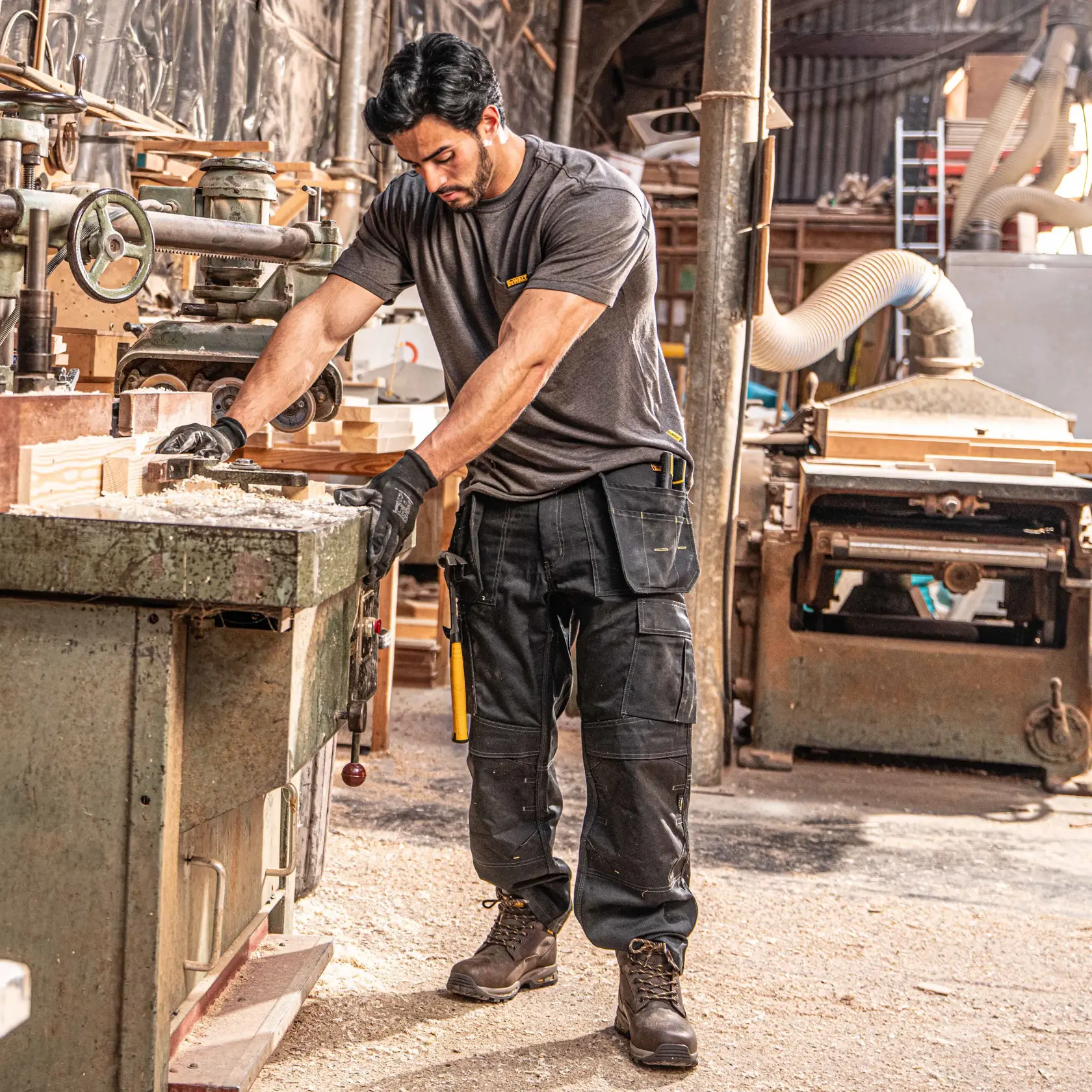 Front view facing left of the DEWALT Protradesman men’s work pants in black on model on location