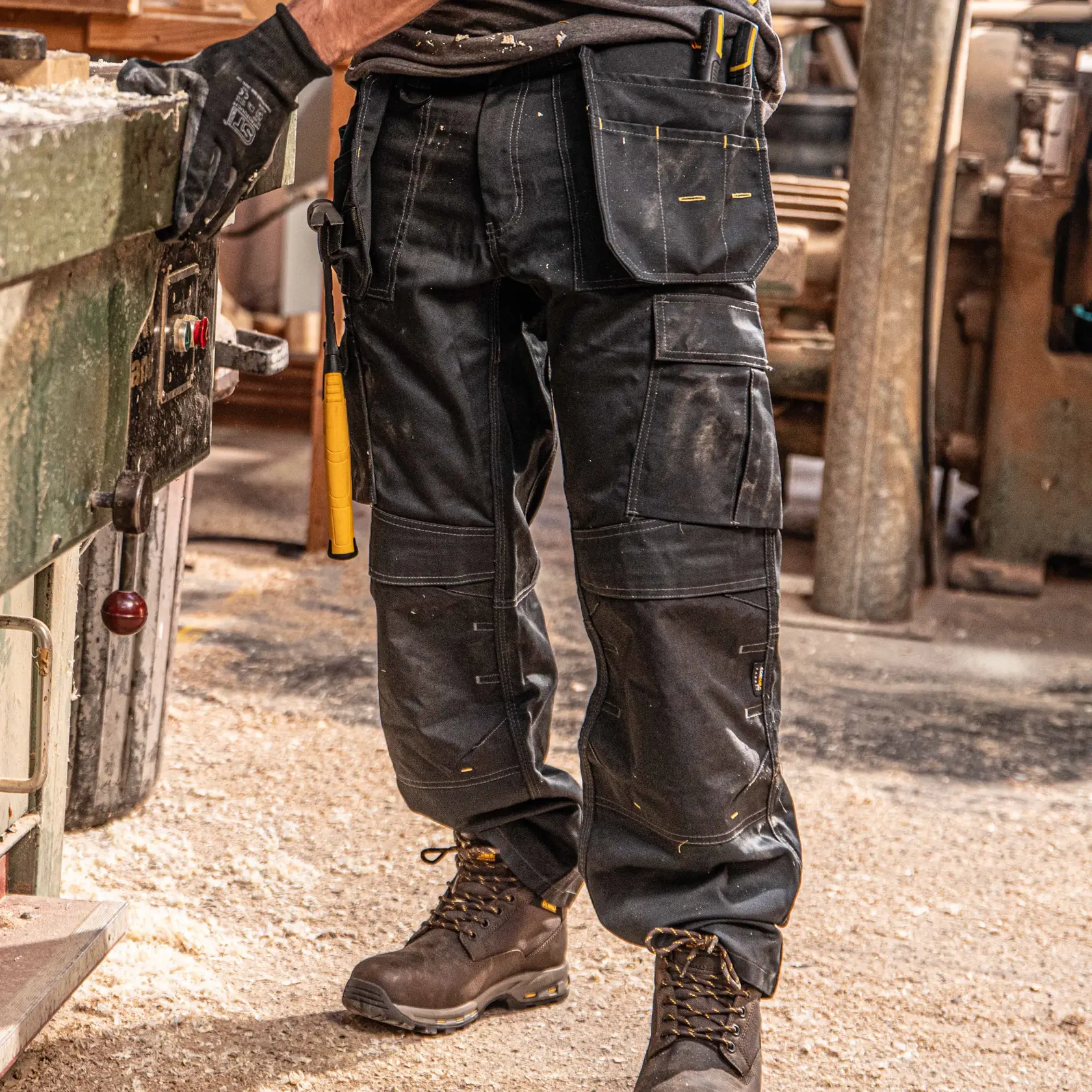 Front view close up facing left of the DEWALT Protradesman men’s work pants in black on model on location