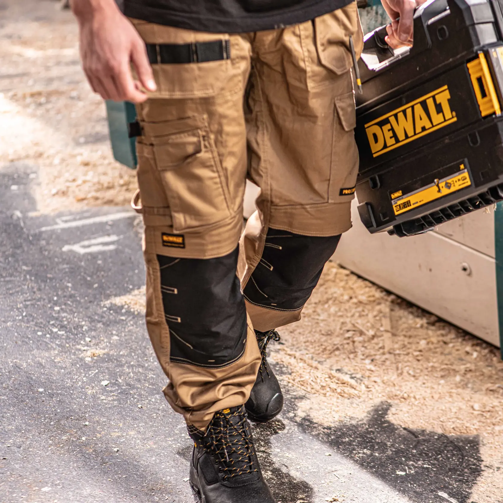 Front view close up facing right of the DEWALT Protradesman men’s work pants in tan on model on location