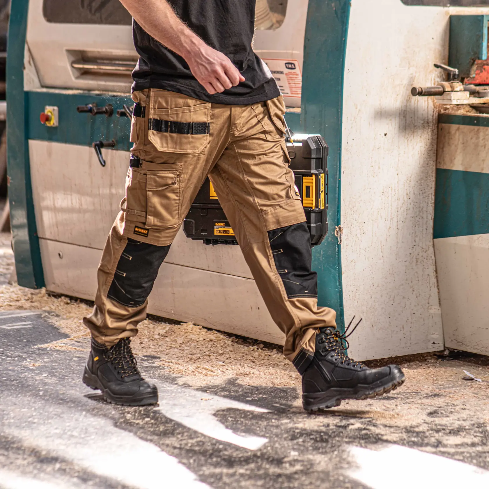 Front view facing right of the DEWALT Protradesman men’s work pants in tan on model on location