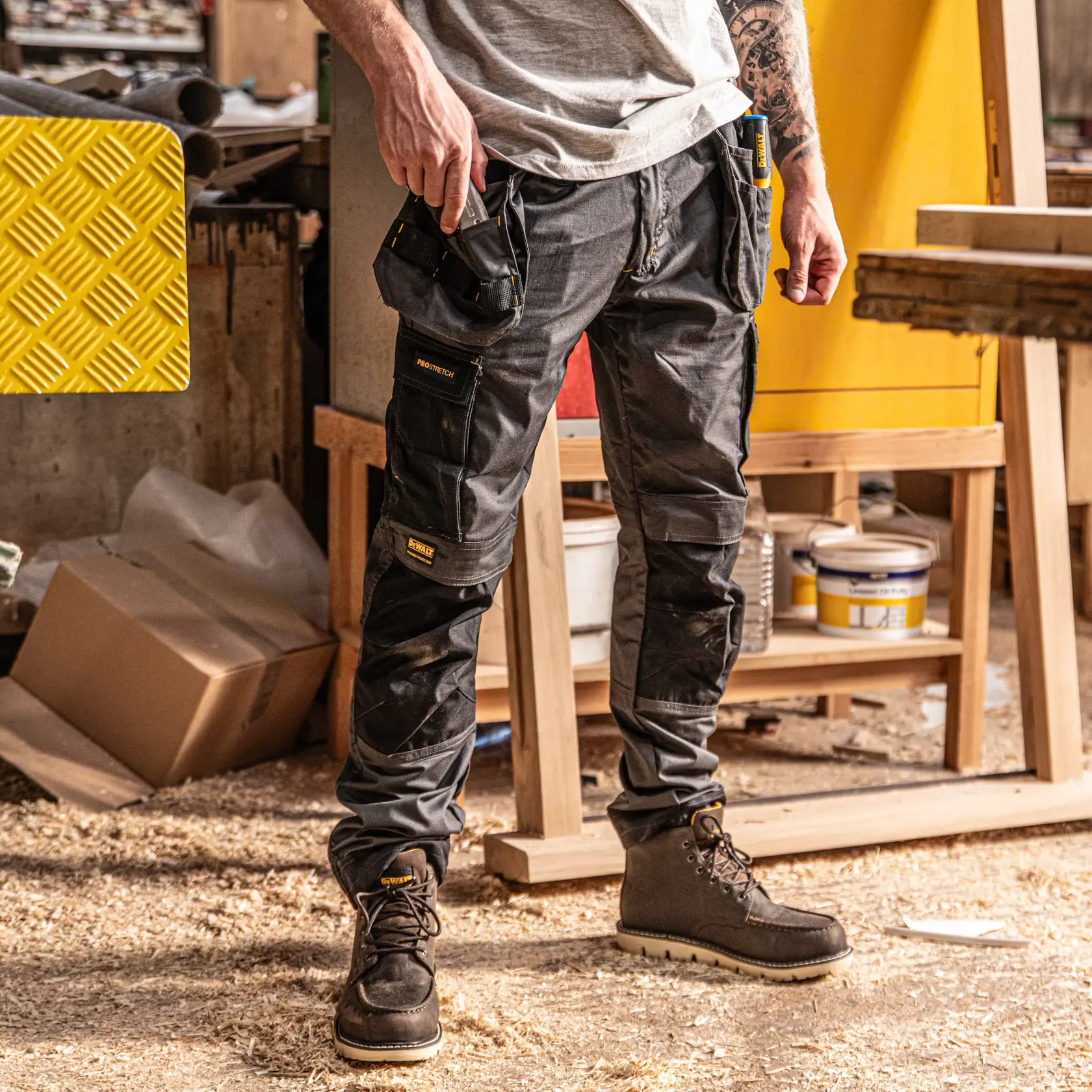 Front view facing right of the DEWALT Barstow men’s work pants in grey/black on model on location