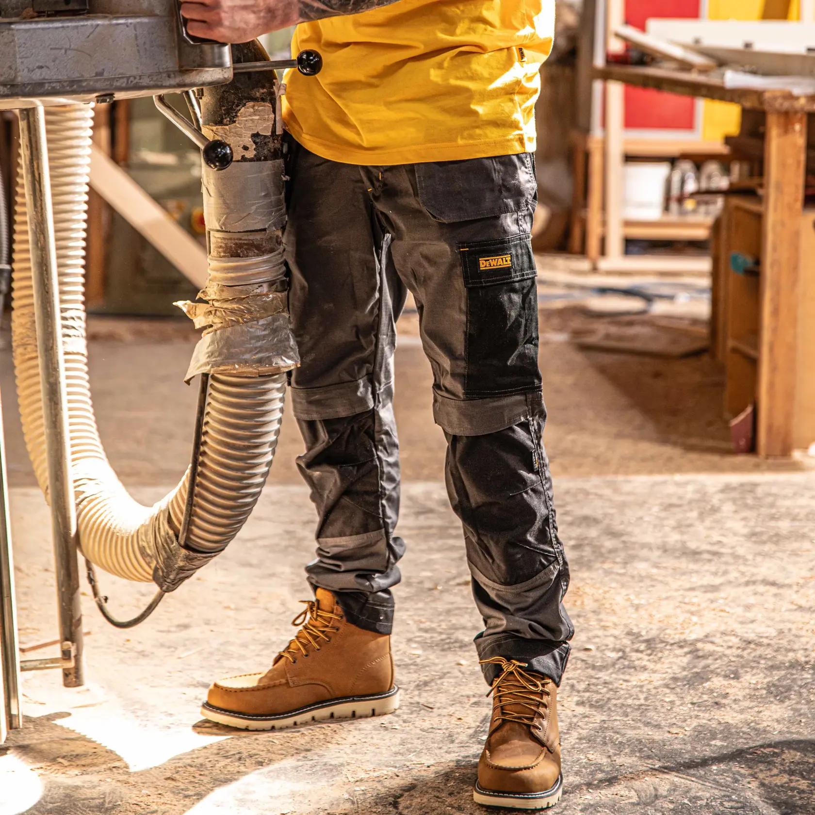 Front view facing left of the DEWALT Barstow men’s work pants in grey/black on model on location