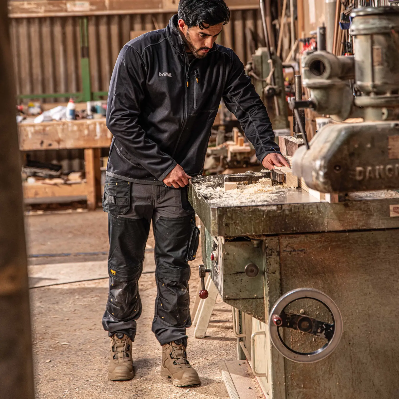 Front view close up facing right of the DEWALT Memphis men’s work pants in grey/black on model on location