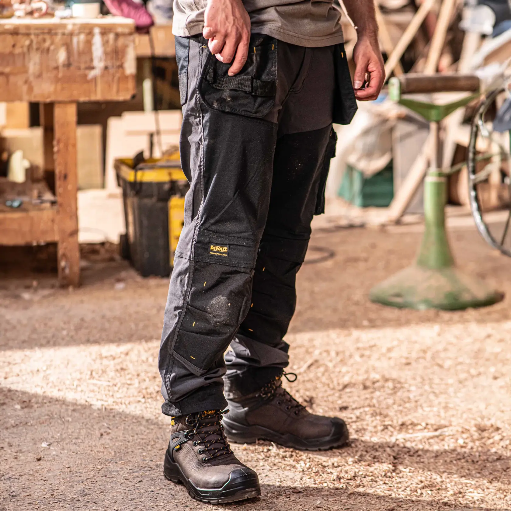 Front view facing right of the DEWALT Memphis men’s work pants in grey/black on model on location
