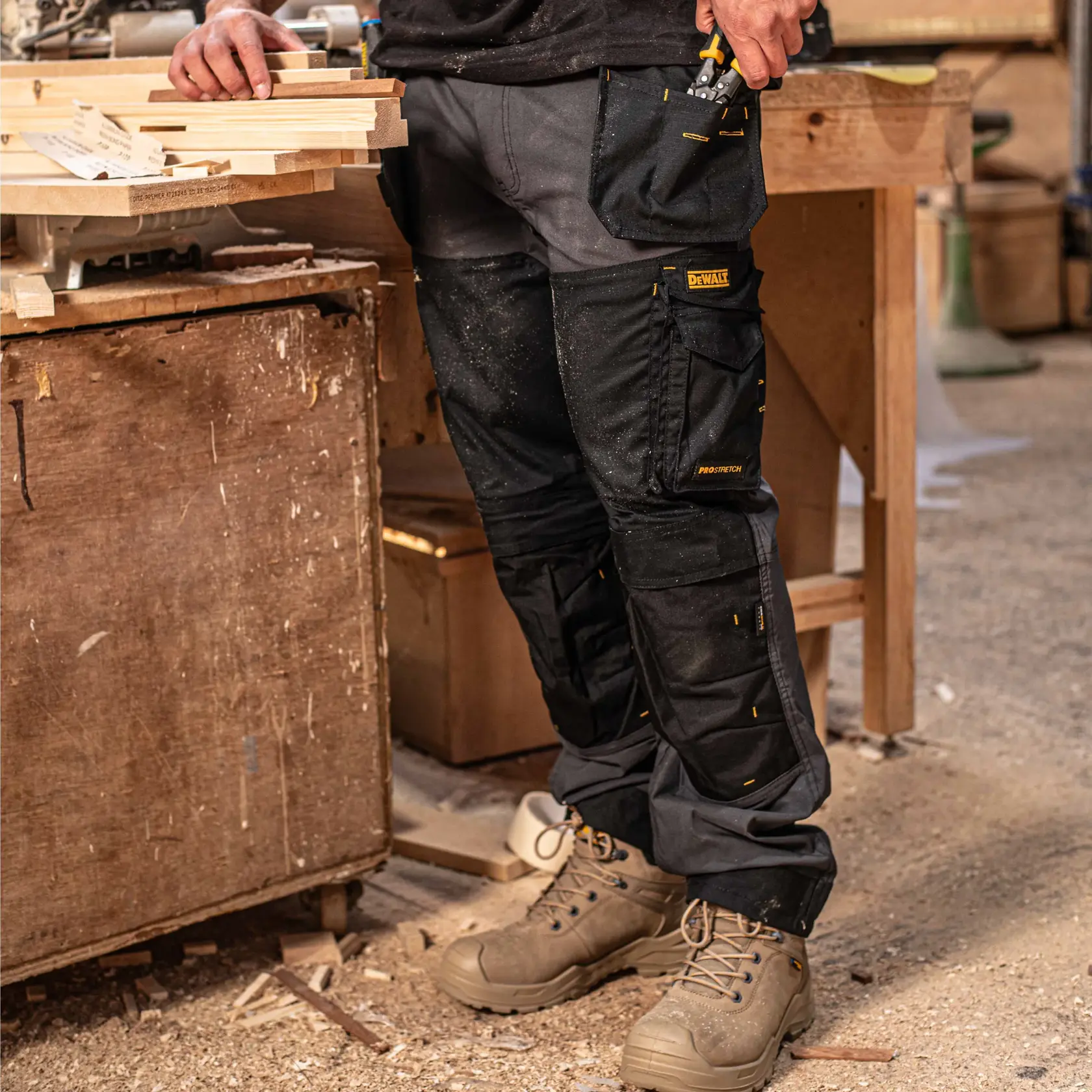 Front view facing left of the DEWALT Memphis men’s work pants in grey/black on model on location